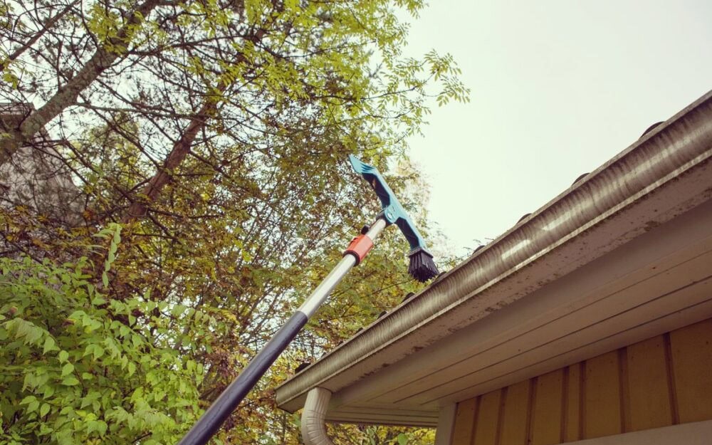 Gutter cleaning in Castlecrag — telescopic brush clearing a metal gutter from ground level