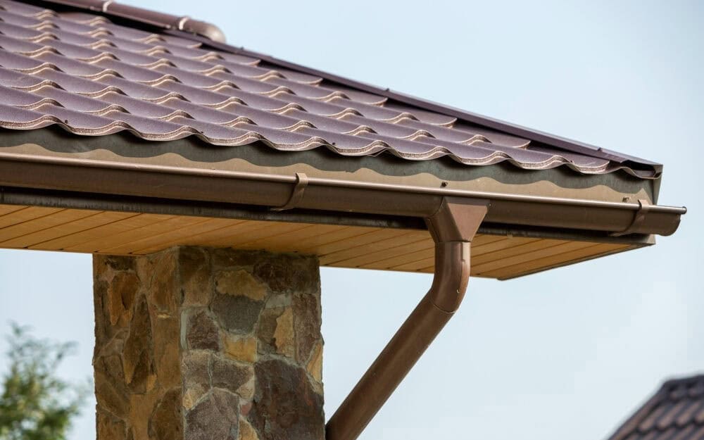 Gutter cleaning in Pymble — brown gutter and downpipe on a tiled roof with timber-lined eaves