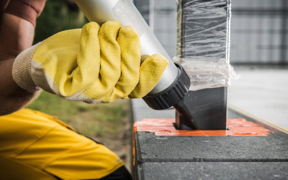 Gutter cleaning in Turramurra — tradesperson in hi-vis applying sealant to metal flashing